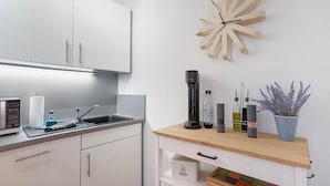 A modern kitchen with white cabinets, a wooden countertop, a coffee maker, and a decorative plant.
