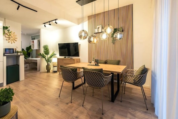 Un comedor moderno con una mesa y sillas de madera, un televisor y un panel decorativo en la pared.