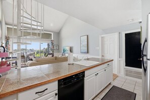 A modern kitchen with white cabinetry, a Bosch dishwasher, and a large island with a sink. - Waterfront Condo 10 Min from Margaritaville! (Montgomery)