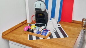 A kitchenette with a coffee machine, a tray with coffee pods, a mug, and a red and blue striped board. - Townhouse Duderstadt: Studio 1 (Duderstadt)
