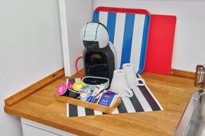 A kitchenette with a coffee machine, a tray with coffee pods, a mug, and a red and blue striped board. - Townhouse Duderstadt: Studio 1 (Duderstadt)