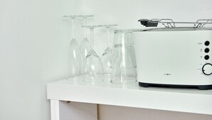 A white toaster on a white shelf with several clear wine glasses. - Townhouse Duderstadt: Studio 1 (Duderstadt)