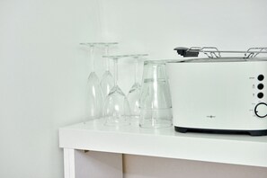 A white toaster on a white shelf with several clear wine glasses. - Townhouse Duderstadt: Studio 1 (Duderstadt)