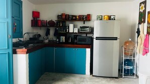 Una cocina con armarios azul verdosos, un refrigerador blanco y diversos electrodomésticos.