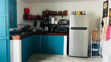 Une cuisine avec des armoires de couleur turquoise, un réfrigérateur blanc et divers appareils de cuisine.