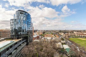 A modern building with a curved glass facade, surrounded by a mix of traditional and modern architecture, with a clear sky above. - Parque Canopy Lakeside Living with Infinity Pool (Melbourne)