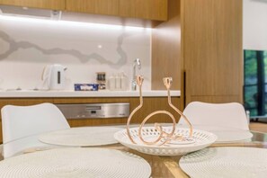 A modern kitchen with a white countertop, stainless steel appliances, and a decorative metal sculpture on the table. - Parque Canopy Lakeside Living with Infinity Pool (Melbourne)