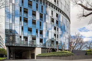 A modern building with a curved facade, large windows, and a landscaped entrance area. - Parque Canopy Lakeside Living with Infinity Pool (Melbourne)