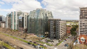 A modern urban area with high-rise buildings, a round building with a curved facade, and a mix of residential and commercial structures. - Parque Canopy Lakeside Living with Infinity Pool (Melbourne)