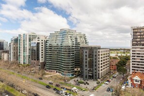 A modern urban area with high-rise buildings, a round building with a curved facade, and a mix of residential and commercial structures. - Parque Canopy Lakeside Living with Infinity Pool (Melbourne)