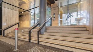 A modern staircase with metal railings and tactile paving at the bottom. - Parque Canopy Lakeside Living with Infinity Pool (Melbourne)