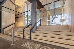 A modern staircase with metal railings and tactile paving at the bottom. - Parque Canopy Lakeside Living with Infinity Pool (Melbourne)