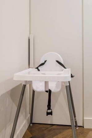 A white baby high chair with a tray, positioned against a wall with a door. - Parque Canopy Lakeside Living with Infinity Pool (Melbourne)