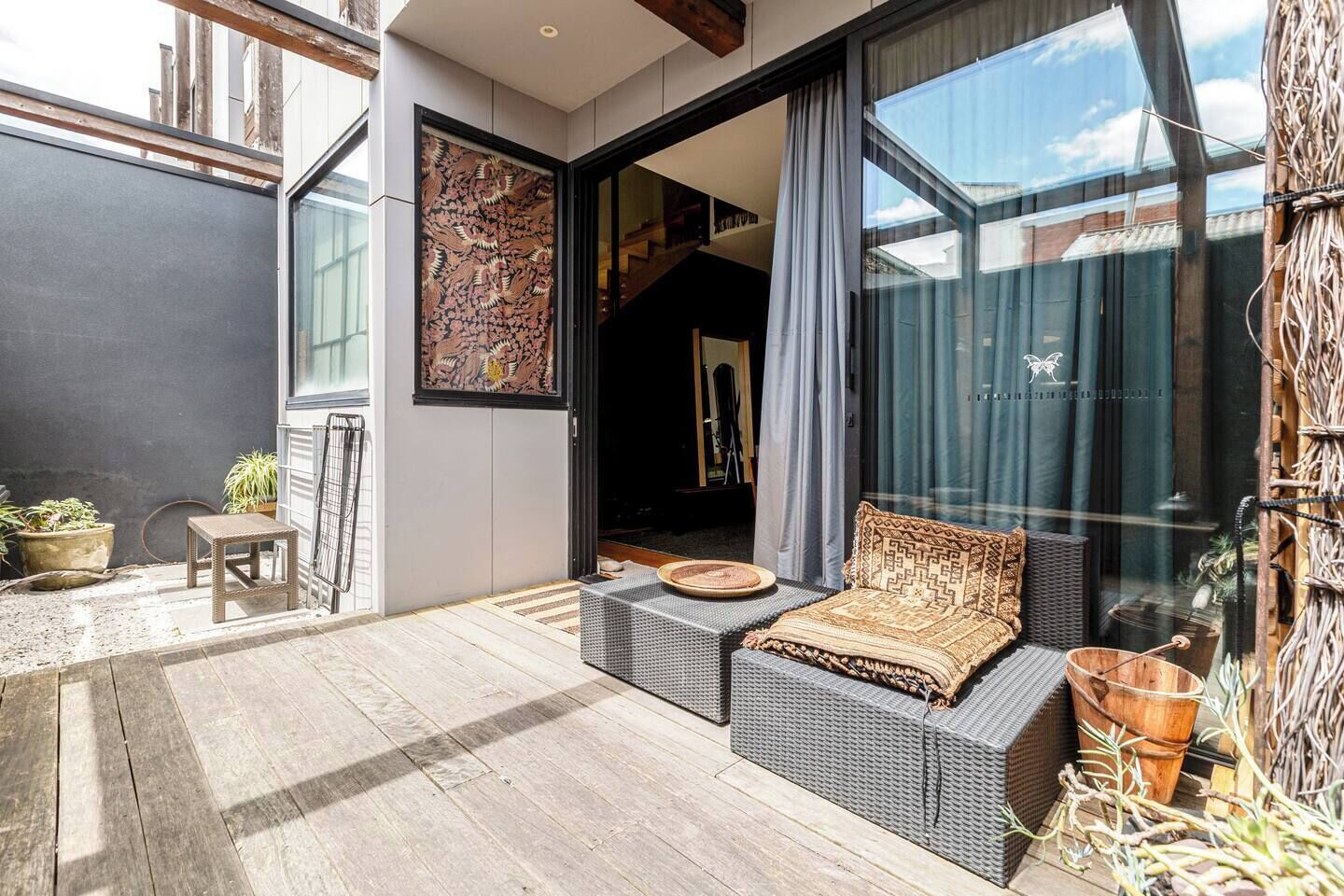 A modern outdoor seating area with wicker furniture, a small table, and potted plants.