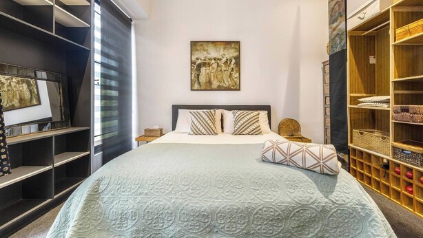 Une chambre à coucher comprenant un lit, un grand tableau, une armoire et une étagère.