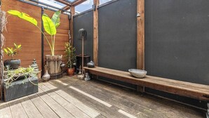 Une terrasse en bois avec un banc et des plantes en pot.