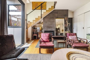 A spacious living area with a staircase, a fireplace, and a view of the outside. - Hikari Haven Richmonds Creative Spirit near Cafs (Richmond)