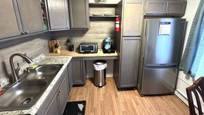 A compact kitchen with a stainless steel refrigerator, a microwave, and a coffee maker on a wooden countertop. - Budget-Friendly 2BR/2BA • Walkable to Events (Virginia Beach)