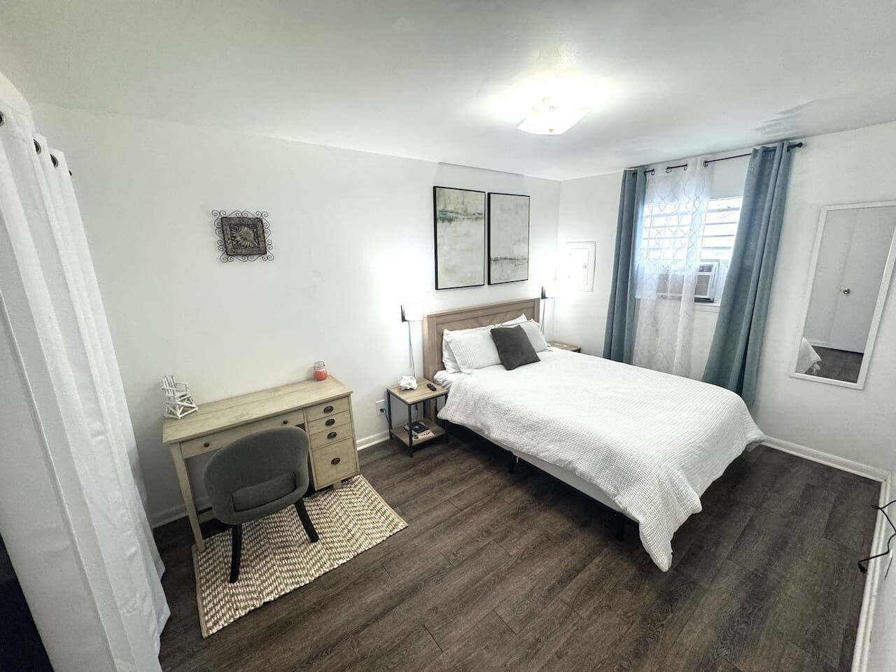 Ein Schlafzimmer mit Bett, Schreibtisch, Stuhl und einem kleinen Nachttisch.