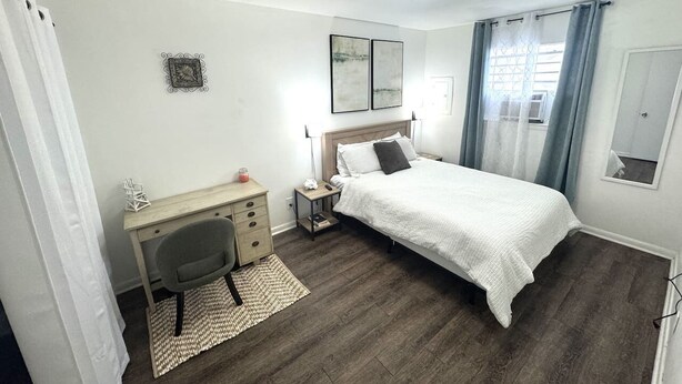 Une chambre à coucher comprenant un lit, un bureau, une chaise et une petite table de chevet.