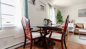 Un coin repas avec une table ronde en verre, des chaises en bois et un canapé blanc.