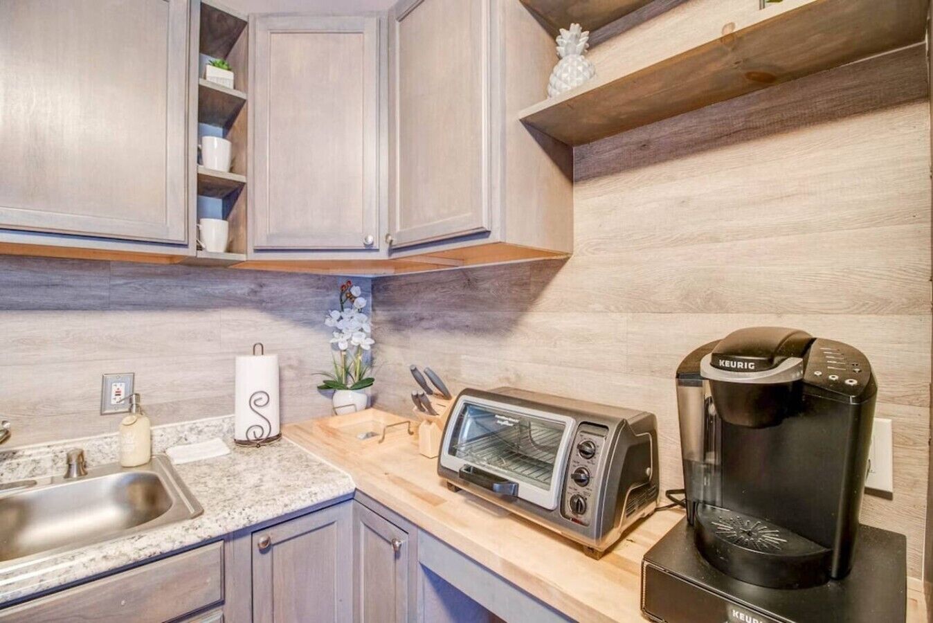 A kitchen with a toaster, coffee maker, and a sink.