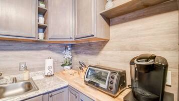 A kitchen with a toaster, coffee maker, and a sink.