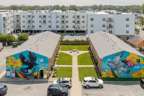 A multi-story building with a central courtyard, parking spaces, and two buildings with murals. - ViBe District 2BR/2BA On 19th Street (Virginia Beach)