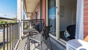 Un balcó amb una taula i cadires, una porta corredissa de vidre i vista al carrer.