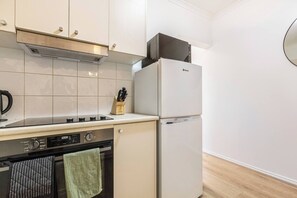 Eine kompakte Küche mit Herd, Backofen und Kühlschrank, mit modernem Design und schlichten Küchenschränken.