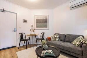 Un saló modern amb un sofà gris, dues cadires negres, una taula rodona petita i una taula de centre amb objectes decoratius.