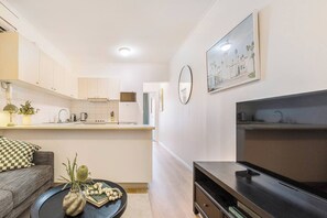 Ein modernes Apartment mit Küche, Wohnbereich und Fernseher.