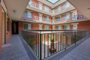 Un edifici d'apartaments amb diversos pisos, balcons, un pati central i un aparcament per bicicletes.