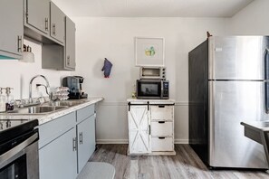 Eine kleine Küche mit einem Edelstahlkühlschrank, einer Mikrowelle und einer Kaffeemaschine.