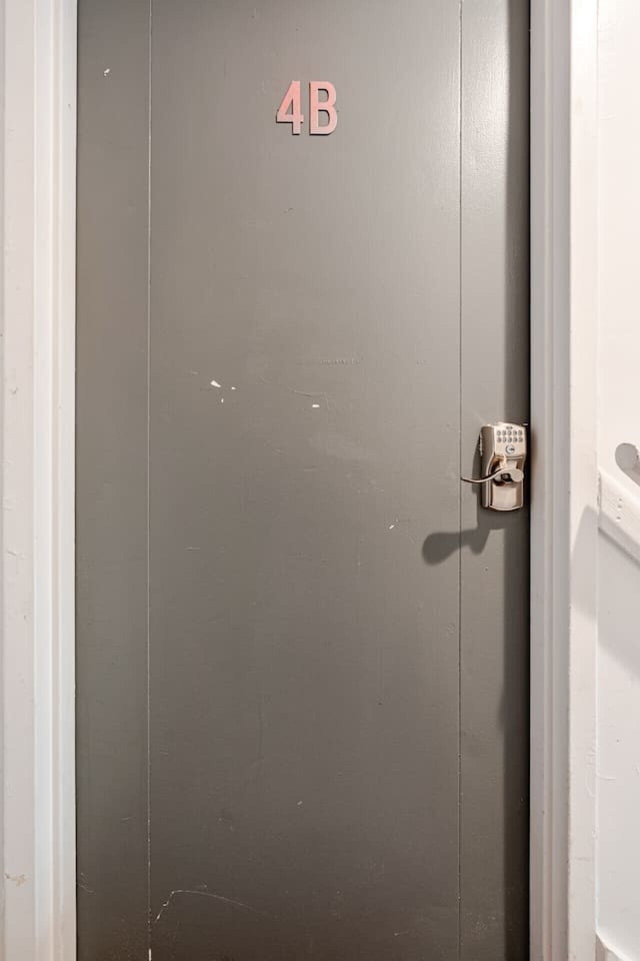 Una puerta gris con un letrero de 4B y un teclado electrónico.