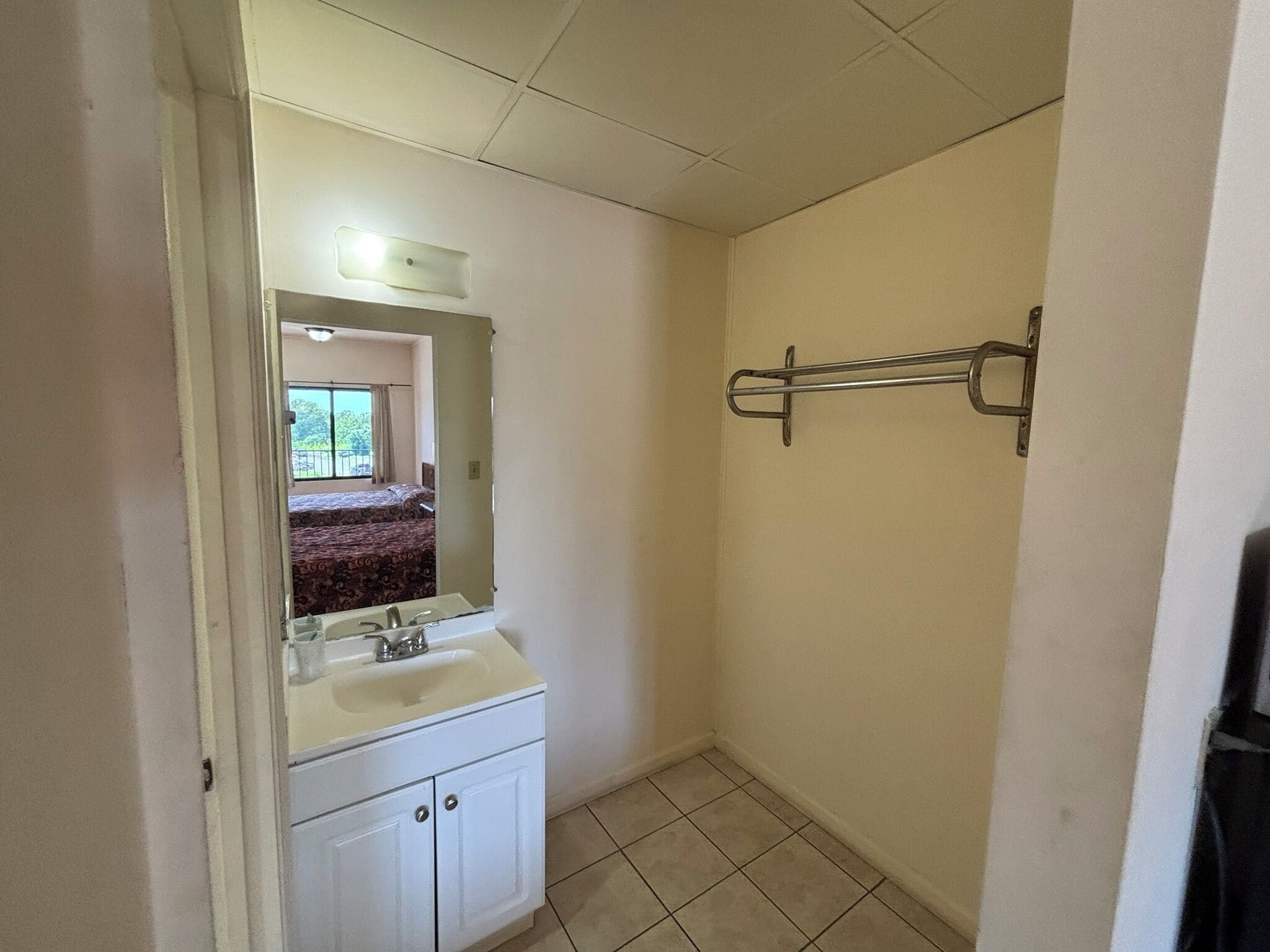 A small bathroom with a sink, mirror, and a towel rack.