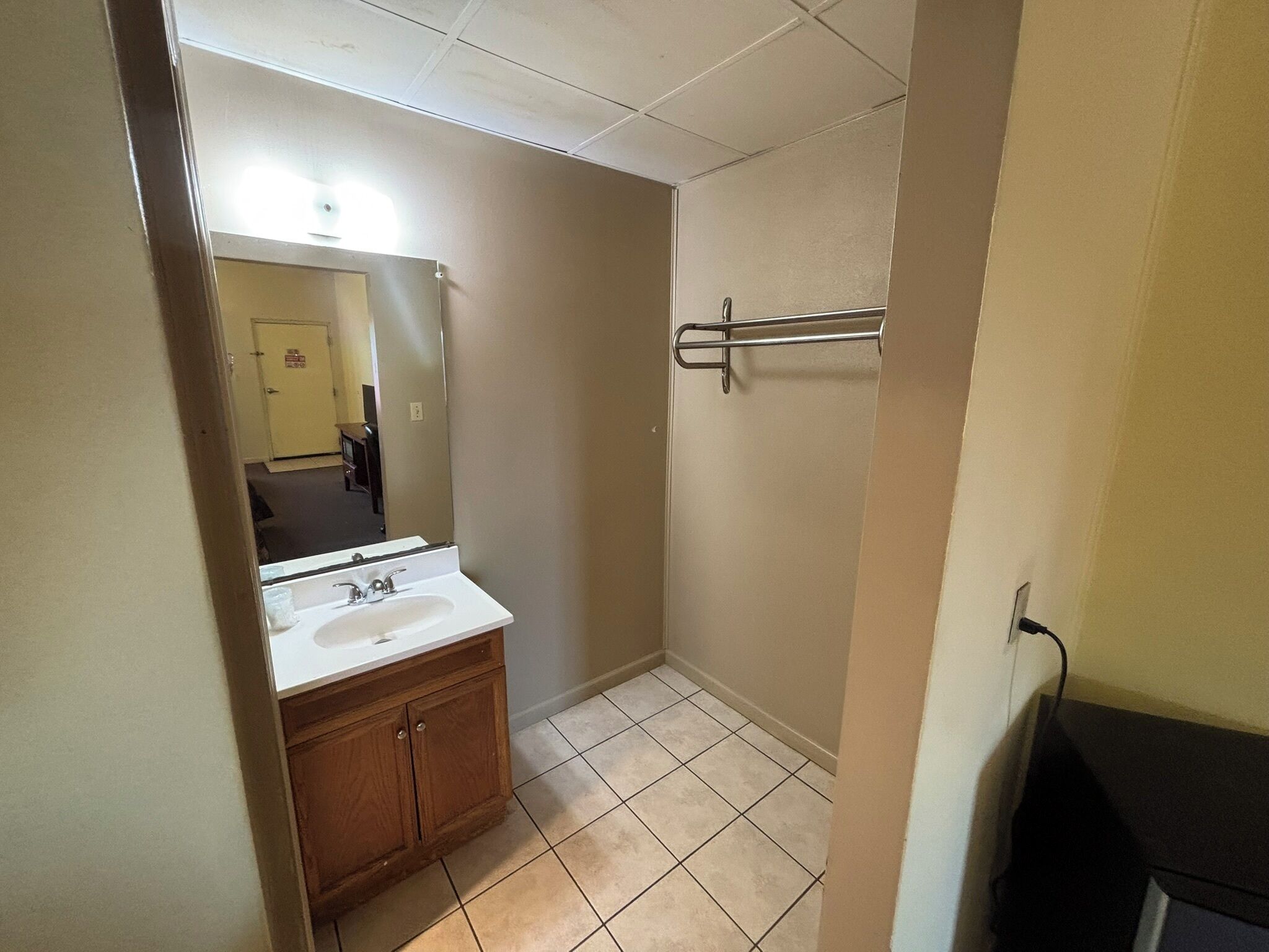 A bathroom with a sink, mirror, and towel rack.