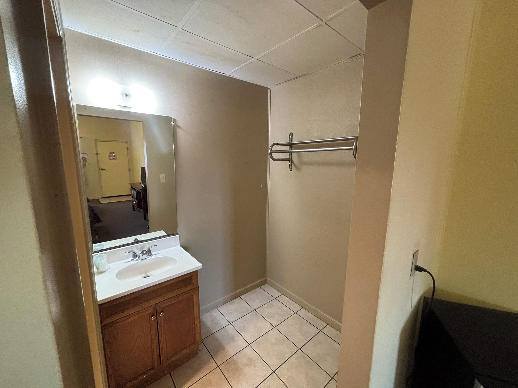 A bathroom with a sink, mirror, and towel rack.