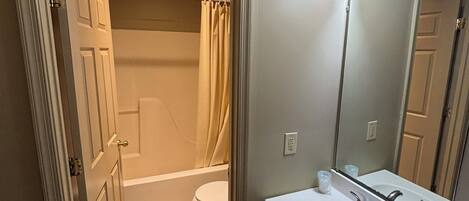 A bathroom with a toilet, sink, and shower area.