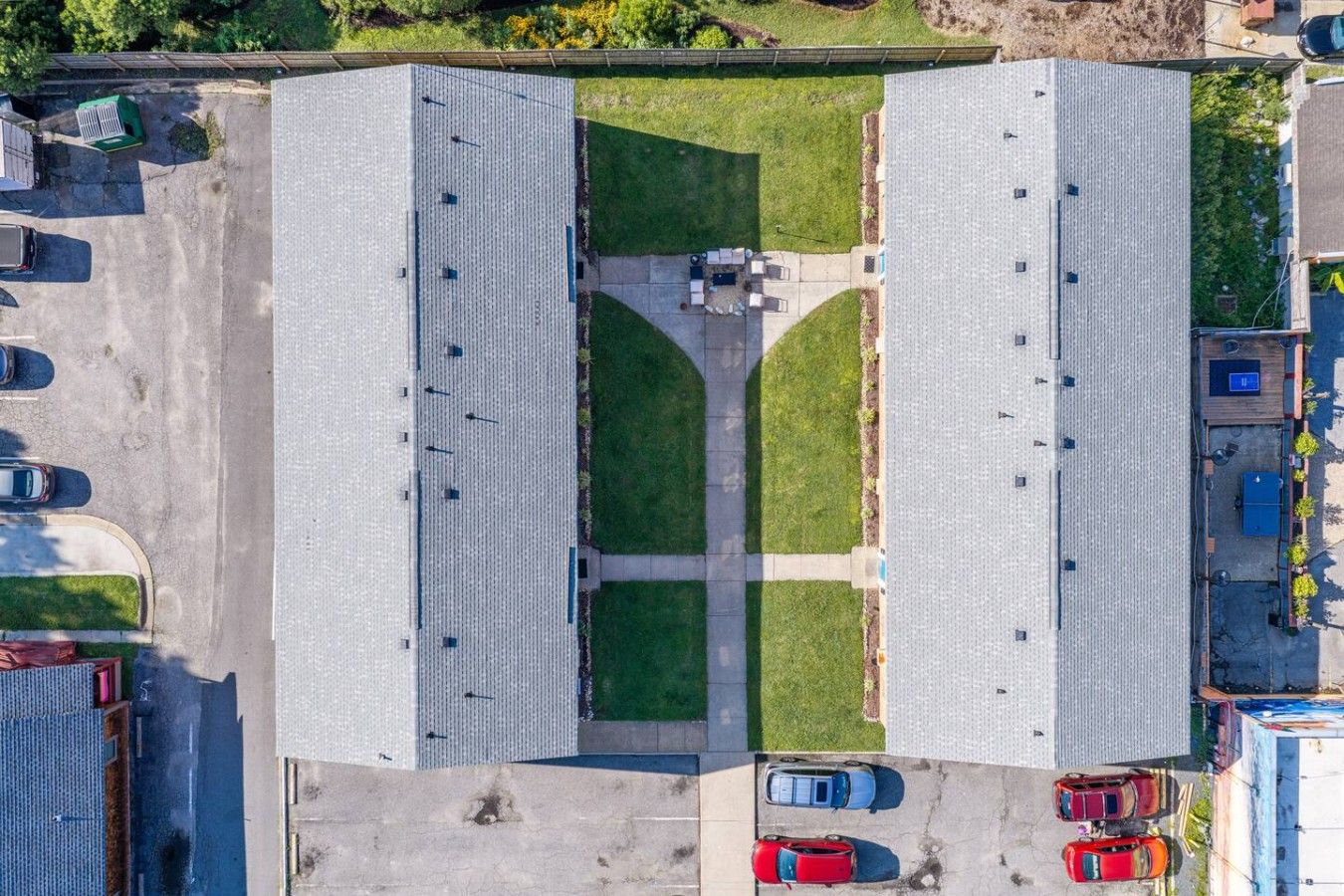 Luchtbeeld van een parkeerplaats met twee grote gebouwen, een gazon en diverse geparkeerde auto's.