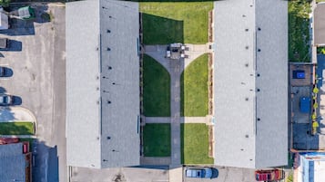 Luchtbeeld van een parkeerplaats met twee grote gebouwen, een gazon en diverse geparkeerde auto's.