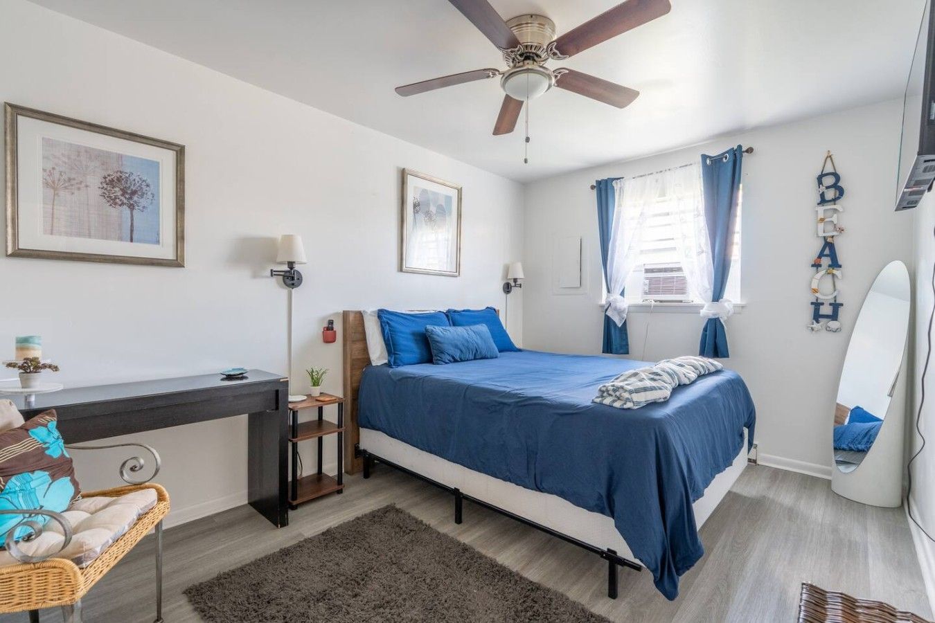 Een slaapkamer met een bed, bureau, stoel en plafondventilator.