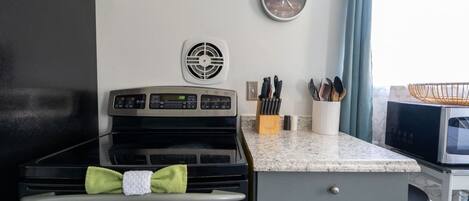 Una cocina con estufa, microondas y un reloj en la pared.