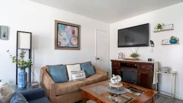 A living room with a sofa, coffee table, fireplace, TV, and decorative items.