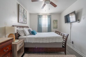 Une chambre à coucher avec un lit, une table de chevet, une lampe et un ventilateur de plafond.