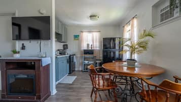 A compact kitchen with a dining area, a built-in oven, and a TV mounted above the counter.