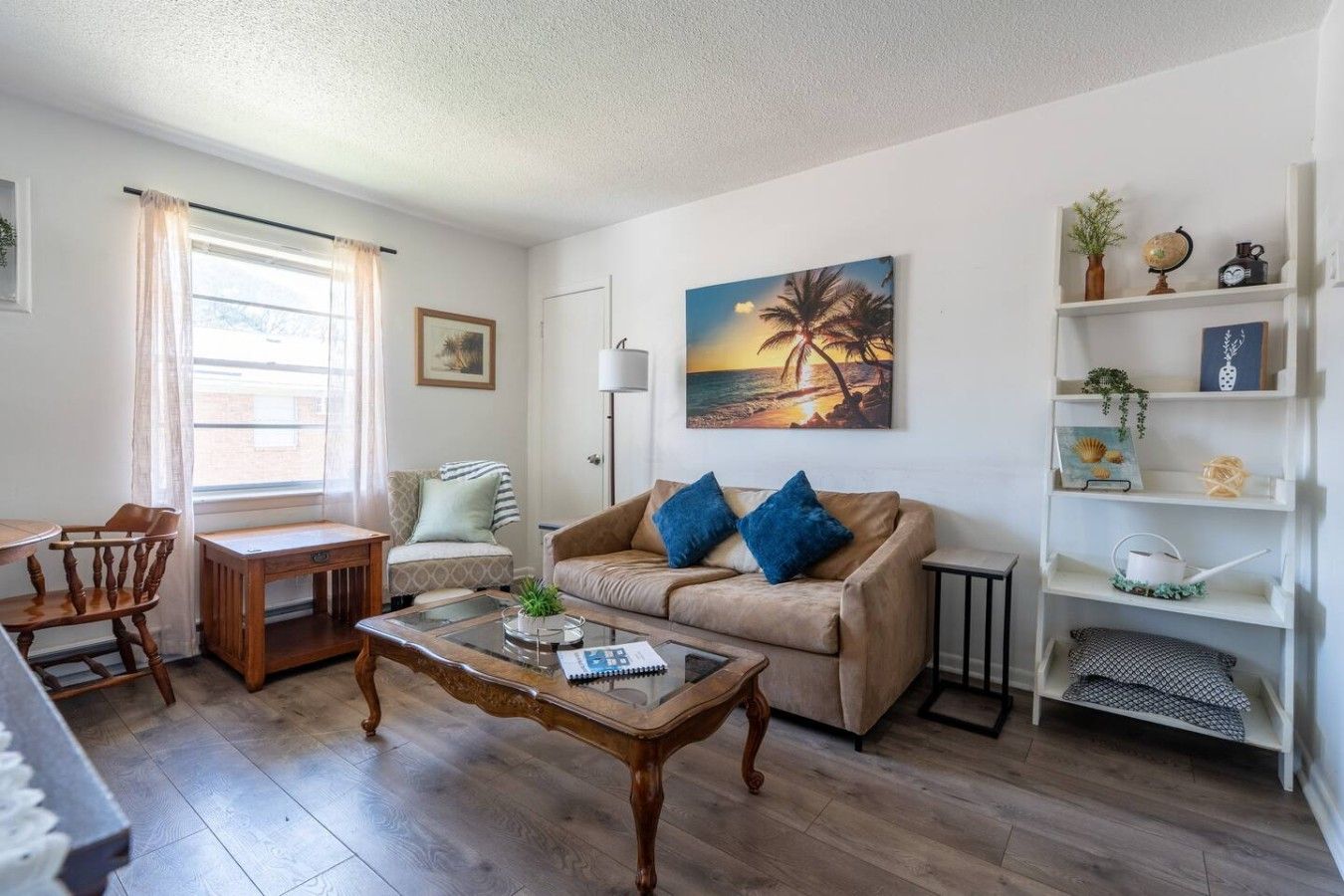 Een woonkamer met een bank, salontafel en een schilderij van een zonsondergang.