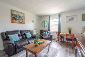 A living room with a sofa, armchairs, a coffee table, and a dining area with a table and chairs. - Mystique Blue 2 BR and Bath APT near Beach (Virginia Beach)