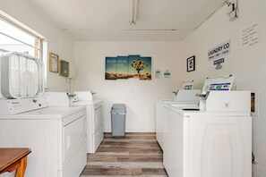 A laundry facility with washers and dryers, a trash bin, and a poster on the wall. - Mystique Blue 2 BR and Bath APT near Beach (Virginia Beach)