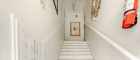 A white staircase with a fire extinguisher mounted on the wall to the right.